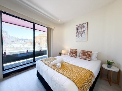 ein Schlafzimmer mit einem Bett mit einem großen Fenster in der Unterkunft QV Spacious 2BR APT CityCentre State Library in Melbourne