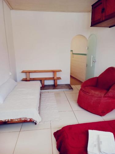 a living room with a red couch and a table at Casa da Áfrika - Suíte Primavera in Itanhandu