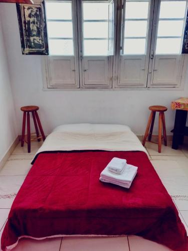 a bedroom with a bed with red blanket and two stools at Casa da Áfrika - Suíte Primavera in Itanhandu