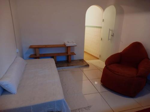 a room with a bed and a chair and a table at Casa da Áfrika - Suíte Primavera in Itanhandu