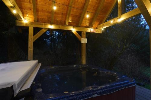 a hot tub under a wooden pergola with lights at Waterfront Chalet in Maple Falls