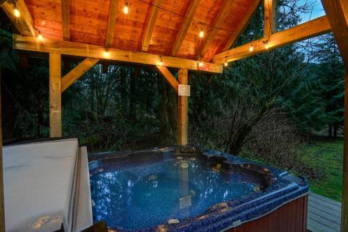 a hot tub under a wooden roof with lights at Waterfront Chalet in Maple Falls