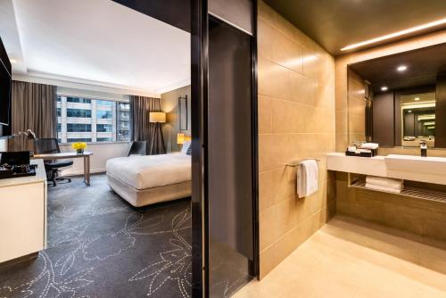 a hotel room with a bathroom with a bed and a sink at PARKROYAL Darling Harbour, Sydney in Sydney