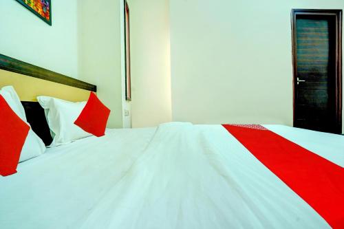 a white bed with red pillows in a room at Hotel O Sunshin Deluxe in Nagpur
