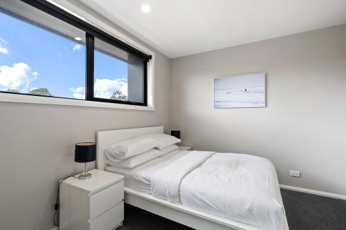 a white bedroom with a bed and a window at Modern 3-Bedroom Townhouse in Quiet Greenway in Tuggeranong