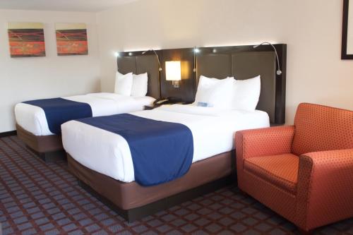 a hotel room with two beds and a chair at Days Inn by Wyndham Woodbury Long Island in Woodbury