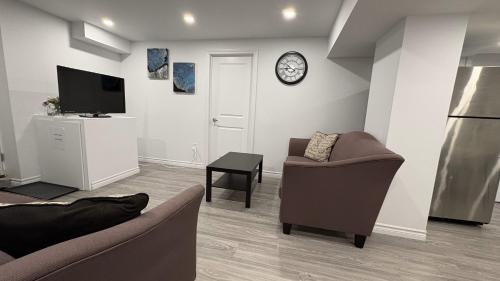 a living room with two couches and a tv at Cozy place, 15 min to Niagara Falls & USA border. in Thorold