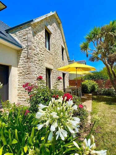 une maison avec un jardin fleuri et un parasol dans l'établissement Villa Kérity-Ki - au coeur du port typique de Kérity, à Penmarcʼh