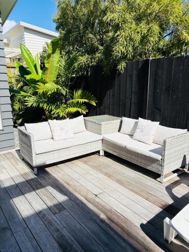 two white couches sitting on a wooden deck at Papamoa Family Beach House in Tauranga