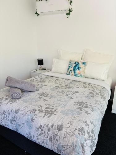a bedroom with a large bed with a blanket and pillows at Papamoa Family Beach House in Tauranga