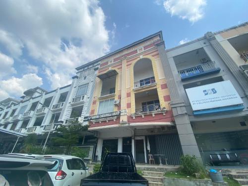 un bâtiment avec des voitures garées devant dans l'établissement Hotel O Mamapapahouse, à Batam Center