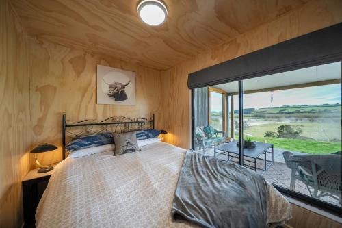 a bedroom with a bed and a large window at Strathvale River Cottage - Winton Holiday Home in Winton