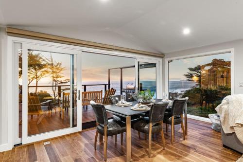 a dining room with a table and chairs and large windows at Entire Private Coastal Retreat - Spectacular Ocean Views wHot Tub in Montara