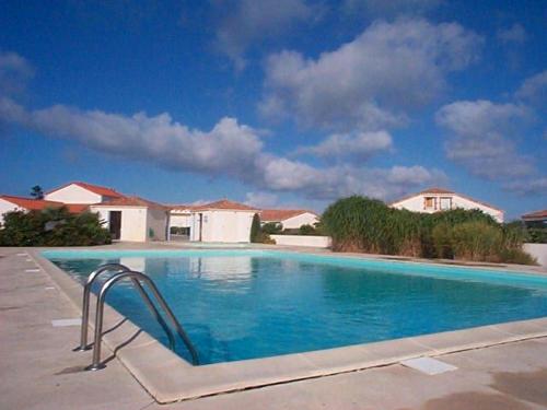 une piscine bleue avec une barre de maintien en métal en face d'une maison dans l'établissement Charmante maisonnette avec piscine commune proche plage - FR-1-194-84, à La Faute-sur-Mer