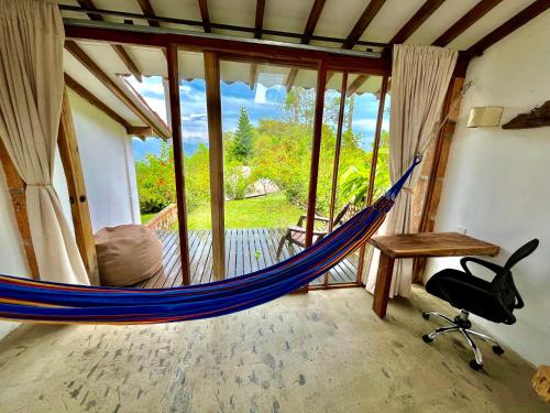 a hammock in a room with a window at Aldea Sabatinga in Manizales