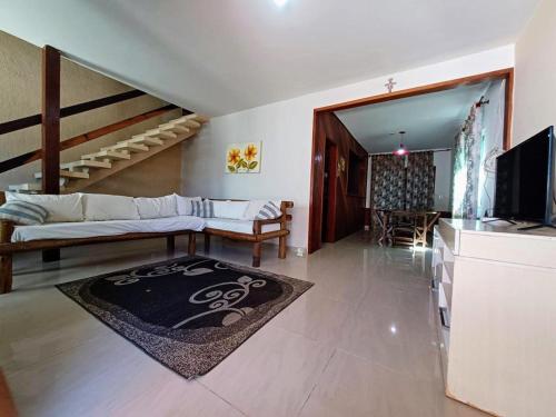 a living room with a couch and a television at Casa com 3 suítes em Cabo Frio com piscina há poucos passos do Mar! in Cabo Frio