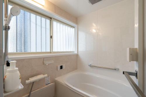 a white bathroom with a tub and a window at APRO STAY Haneda kamata5 in Tokyo