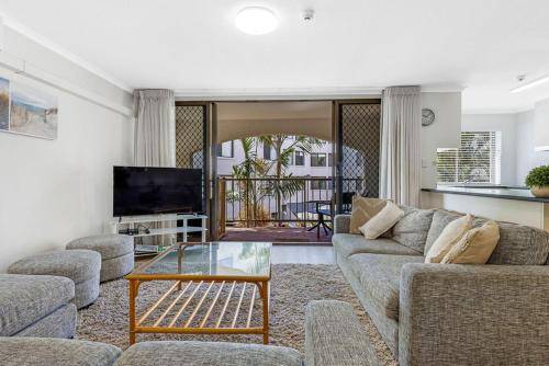 a living room with a couch and a glass table at Kalua Holiday Apartments in Maroochydore