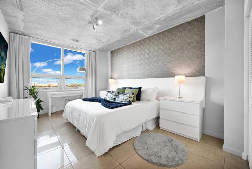 a white bedroom with a bed and a large window at Exclusive unit in Miami Sunshine in Miami
