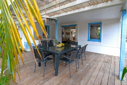 a patio with a black table and chairs on a deck at Villa Les Koulirous in Sainte-Anne