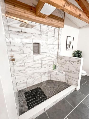 a bathroom with a shower with white marble walls at Cabin Sweet Cabin in Burlington