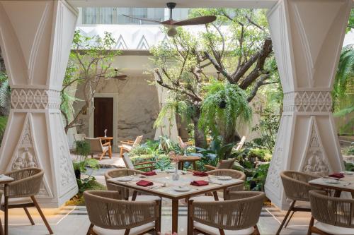 a dining room with tables and chairs and a garden at La Plante Siem Reap in Siem Reap
