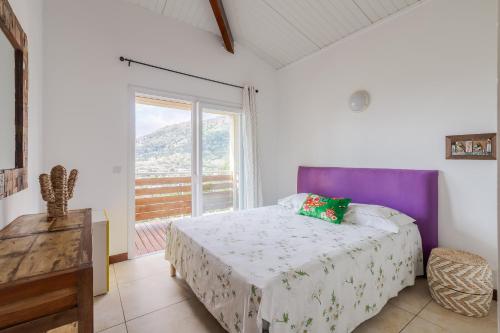 a bedroom with a bed and a large window at Villa Cosy in Dumbéa