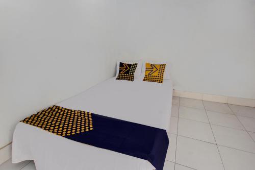 un letto bianco con due cuscini neri e gialli sopra di OYO Life 93153 Kos Jenggala a Tanjung
