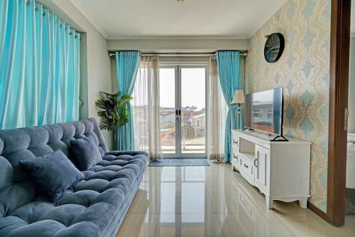 a living room with a blue couch and a tv at OYO Life 93097 Apartemen Gateway Pasteur By Kaisar Room in Bandung