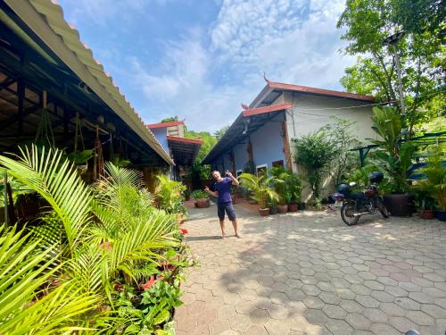 a man standing in front of a house at Derm Svay Guesthouse - yoga & cafe in Kampot
