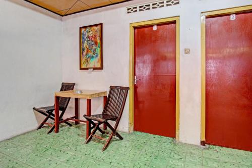 a room with a table and two chairs and a red door at Hotel O Jaya Kusuma in Prambanan