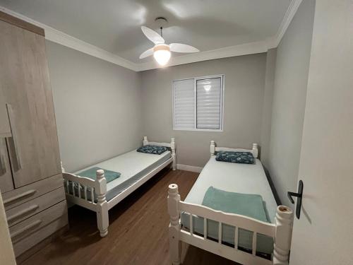 two twin beds in a room with a ceiling fan at Apartamento Maitinga aconchegante in Bertioga