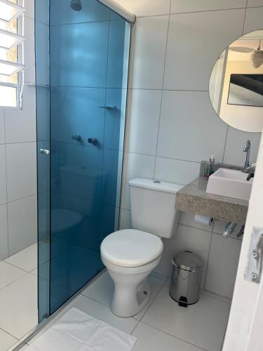 a bathroom with a toilet and a glass shower at Apartamento Maitinga aconchegante in Bertioga