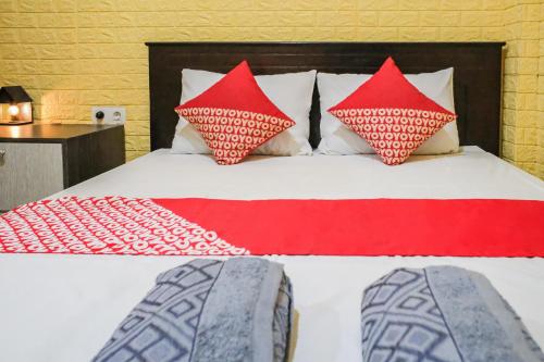 a bed with red and white pillows on it at OYO 93333 Rama Home Stay in Jayapura