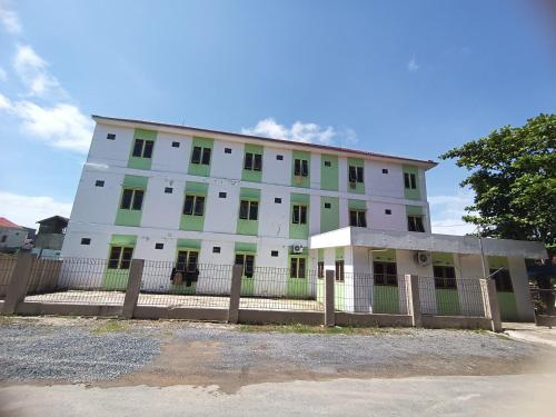 een wit gebouw met een hek ervoor bij Hotel O Pondok Kula Rumbih Syariah in Sungairasau