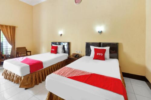 two beds in a hotel room with red pillows at Capital O 93391 Golden Manggis Hotel Near SMKN 1 Lingsar in Narmada