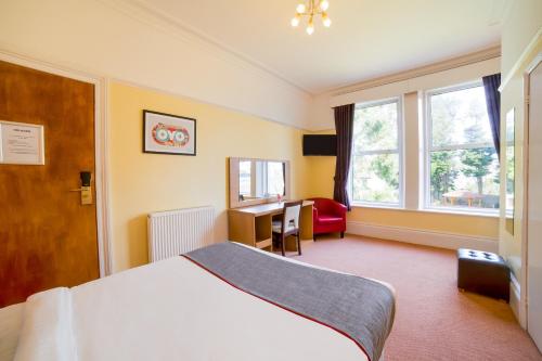 a hotel room with a bed and a desk and window at OYO Eagle House Hotel, St Leonards Hastings in St. Leonards