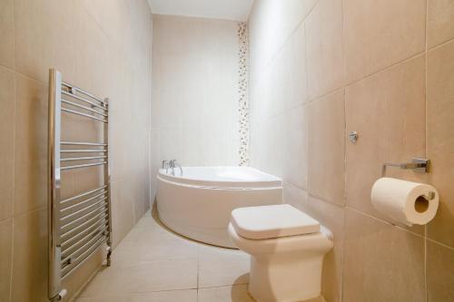 a white bathroom with a toilet and a bath tub at OYO Eagle House Hotel, St Leonards Hastings in St. Leonards