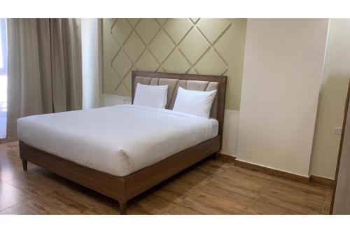 a bed with white sheets and pillows in a room at OYO Townhouse 156 Rose Hotel Apartments in Muscat