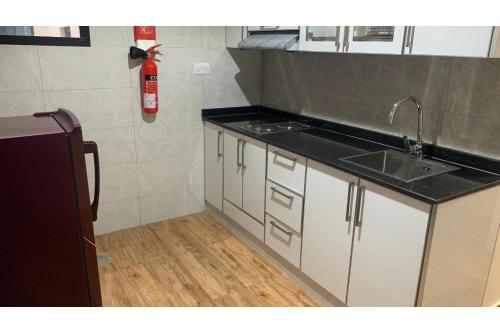 a kitchen with a sink and a fire extinguisher at OYO Townhouse 156 Rose Hotel Apartments in Muscat