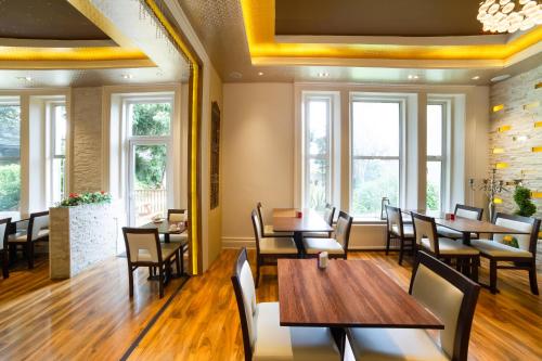 a restaurant with wooden tables and chairs and windows at OYO Eagle House Hotel, St Leonards Hastings in St. Leonards