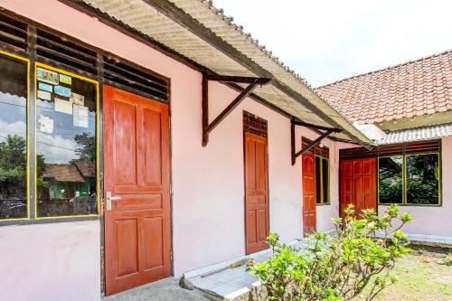 a house with red doors and windows at Hotel O Pondok Wisata Sekar KemuningNearWonogondang Camp ( Bumi Perkemahan Wonogondang ) in Yogyakarta