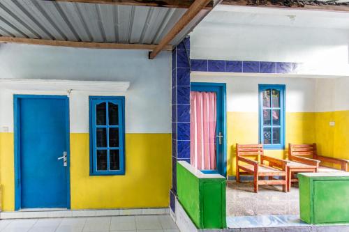 a room with blue and yellow walls and chairs at Hotel O Kawi Homestay in Praya