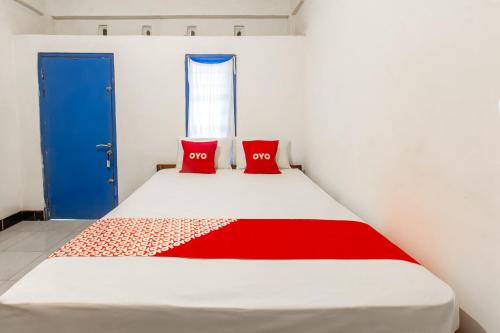 a bedroom with a bed with two red pillows on it at Hotel O Kawi Homestay in Praya