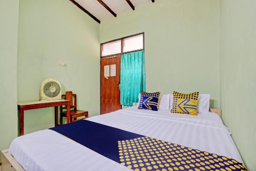 a bedroom with a bed with blue and yellow pillows at Hotel O Jaya Kusuma in Prambanan