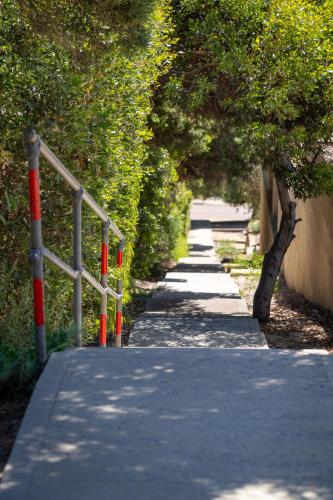 a walkway with red poles and trees on a sidewalk at Ocean Views I Private Properties in Yallingup