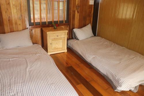 two beds in a small room with wooden floors at Atash Eco Village Homestay Van Hoi in Quân Khê