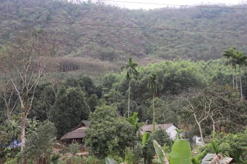 a house in the middle of a mountain with trees at Atash Eco Village Homestay Van Hoi in Quân Khê