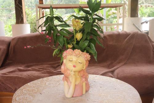 a statue of a woman sitting on a table with a plant at Atash Eco Village Homestay Van Hoi in Quân Khê
