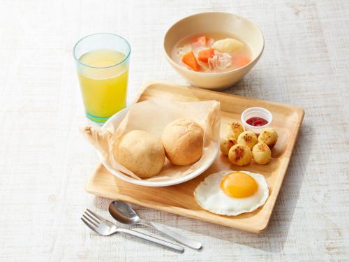 a tray with eggs and biscuits and a glass of orange juice at Takatakiko Glamping Resort in Tsurumai